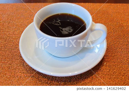 一杯溫熱的黑咖啡放在餐墊上。 一杯溫熱的黑咖啡放在餐墊上。 141629402