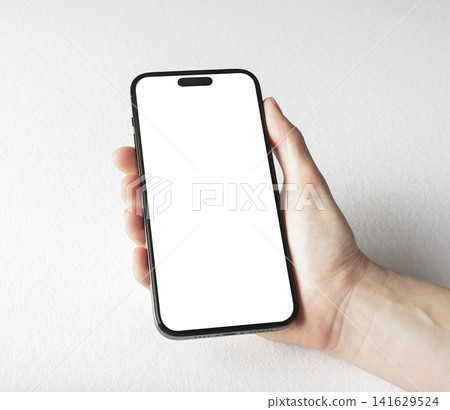 A hand holds a mockup phone with a blank white screen against a plain grey background. The template A hand holds a mockup phone with a blank white screen against a plain grey background. The template 141629524