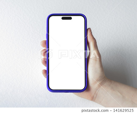 A hand holds a mockup phone with a blank white screen and blue frame against a plain grey background A hand holds a mockup phone with a blank white screen and blue frame against a plain grey background 141629525