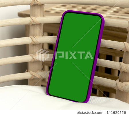 Blank smartphone mockup in purple case on wicker chair. Angled mobile phone with green screen and copy space. App design, advertising, and product presentation template.. 141629556