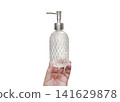 A clear glass perfume bottle with a diamond pattern is in the man's hand. 141629878
