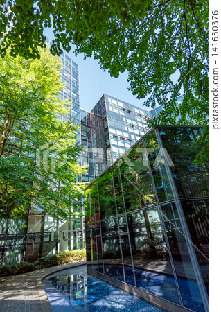 Modern glass office buildings with trees at Stieglmaierplatz in Munich, Bavaria, contemporary corporate architecture with reflective facades and green courtyard under blue sky Modern glass office buildings with trees at Stieglmaierplatz in Munich, Bavaria, contemporary corporate architecture with reflective facades and green courtyard under blue sky 141630376