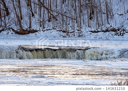 Water flows over a frozen edge in a cold winter setting by a river Water flows over a frozen edge in a cold winter setting by a river 141631210