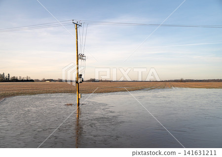 Water from melting ice creates floods in fields near power lines and trees in spring. 141631211