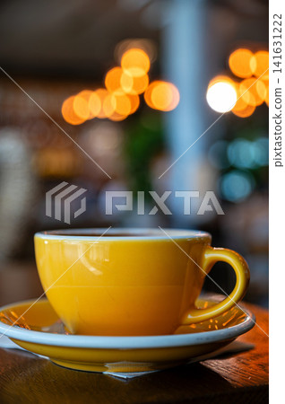 Coffee cup on a table in a cafe with blurred lights in the background Coffee cup on a table in a cafe with blurred lights in the background 141631222