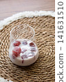 Close-up of creamy iced coffee with frozen cherry juice ice cubes in a transparent glass. Homemade refreshing beverage perfect for hot summer days. 141631510