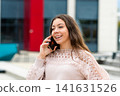 Young Woman Smiling While Speaking on the Phone Outside in a City During Daytime 141631526