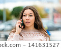 Young Woman Smiling While Speaking on the Phone Outside in a City During Daytime 141631527