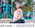 Young Woman Relaxing by a Fountain in an Urban Park During a Sunny Afternoon 141631529
