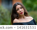Young Woman Smiling in Off-Shoulder Top During Golden Hour in Urban Setting 141631531