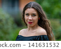 Young Woman With Long Hair Wearing Off-Shoulder Top Posing Outdoors in Urban Setting 141631532