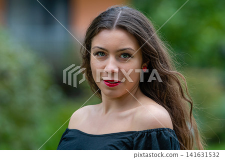 Young Woman With Long Hair Wearing Off-Shoulder Top Posing Outdoors in Urban Setting Young Woman With Long Hair Wearing Off-Shoulder Top Posing Outdoors in Urban Setting 141631532