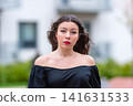 Young Woman With Long Hair Poses Outdoors in City During Autumn Afternoon 141631533