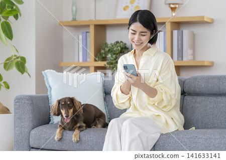 A young woman using her smartphone and her pet dog sitting beside her. A young woman using her smartphone and her pet dog sitting beside her. 141633141
