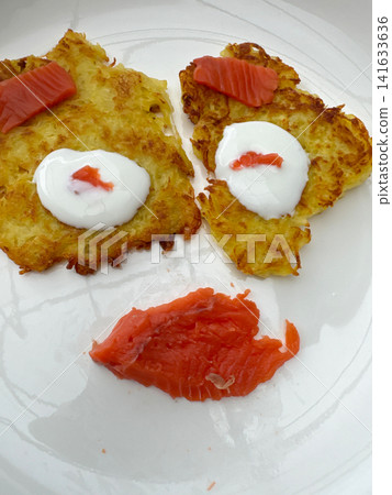 Playful food face made with potato pancakes and salmon Playful food face made with potato pancakes and salmon 141633636