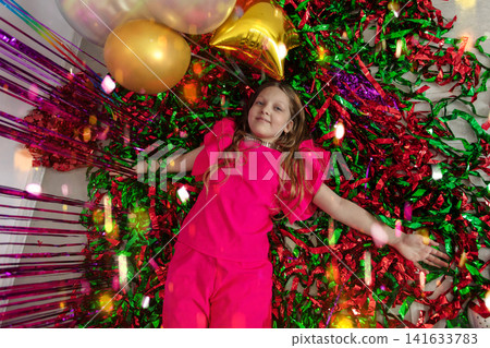 Girl celebrates on colorful confetti ground during a joyful party atmosphere filled with balloons and decorations Girl celebrates on colorful confetti ground during a joyful party atmosphere filled with balloons and decorations 141633783