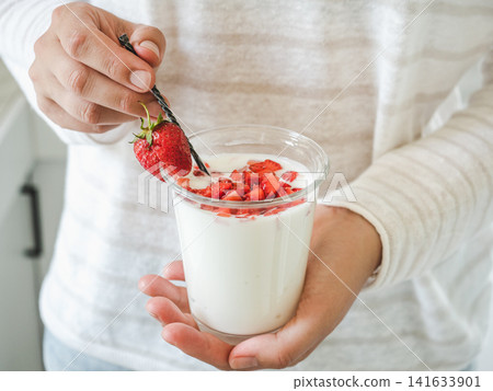 Hands stirring strawberry yogurt with a spoon Hands stirring strawberry yogurt with a spoon 141633901