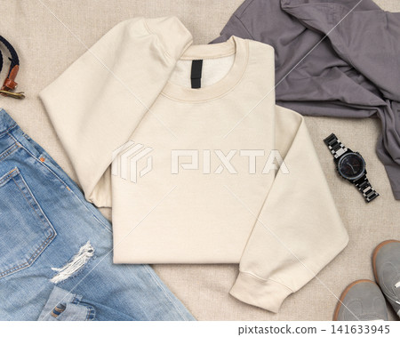 Blank beige unisex sweatshirt mockup, folded crewneck flat lay with denim jeans and mens accessories Blank beige unisex sweatshirt mockup, folded crewneck flat lay with denim jeans and mens accessories 141633945