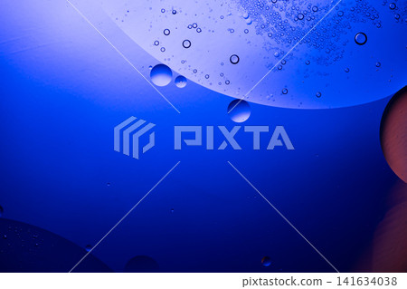 Oil drops and bubbles creating an abstract pattern on a blue liquid surface Oil drops and bubbles creating an abstract pattern on a blue liquid surface 141634038
