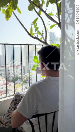 Man enjoys coffee on a balcony Man enjoys coffee on a balcony 141634165