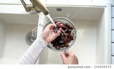 Female hands wash dried dates Female hands wash dried dates 141634173