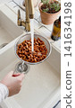 Woman washes almonds in a metal colander 141634198