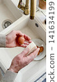 Man washes eggs with a sponge 141634199