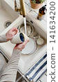 Man washes dishes in a kitchen sink 141634200