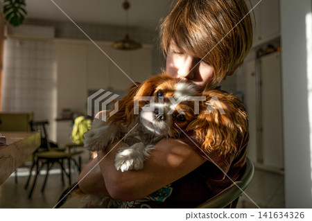Boy reading book with his pet dog Cavalier King Charles Spaniel, Reading education, school preparation, back to school Boy reading book with his pet dog Cavalier King Charles Spaniel, Reading education, school preparation, back to school 141634326