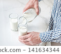 Man's hand pours fresh milk 141634344