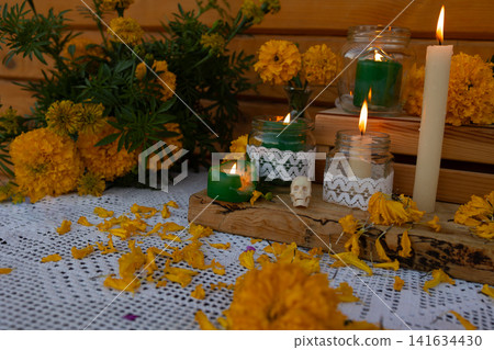 Day of Dead altar featuring marigold flowers, lit candles, lace cloth, wooden accents, small skull arranged for cultural remembrance and warm ceremonial tribute Day of Dead altar featuring marigold flowers, lit candles, lace cloth, wooden accents, small skull arranged for cultural remembrance and warm ceremonial tribute 141634430