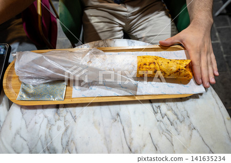 Istanbul, turkey. August 2, 2025. A person holds a street food durum kebab wrap, featuring savory meat and lavash, served on a tray in istanbul Istanbul, turkey. August 2, 2025. A person holds a street food durum kebab wrap, featuring savory meat and lavash, served on a tray in istanbul 141635234