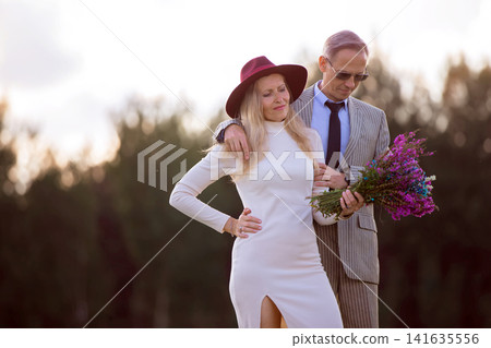 Elegant couple enjoying a romantic moment in a natural setting during golden hour Elegant couple enjoying a romantic moment in a natural setting during golden hour 141635556