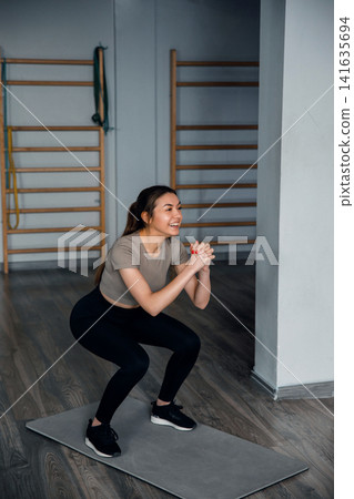 Beautiful woman doing squat exercise on mat in gym wearing sportswear with strength training and healthy fitness lifestyle concept 141635694