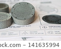 MJF 3D printed parts with ridged pattern on technical blueprint background 141635994