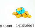 A blue miniature shopping basket overflowing with gold dollar coins on a white background. Concept for consumerism, wealth, commerce, and grocery spending. High-quality studio shot. 141636004