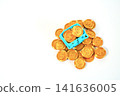Miniature blue shopping basket overflowing with gold dollar coins on a clean white background. Concept for retail sales, consumer spending, e-commerce, and financial investment growth. 141636005