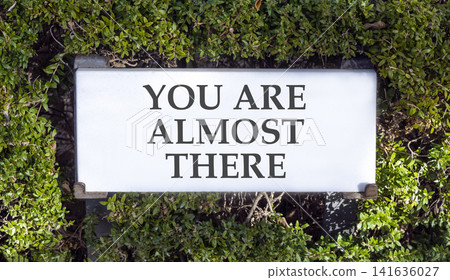 You are almost there symbol. Concept words You are almost there on beautiful white sign plate. Beautiful green trees background. Business You are almost there motivational support concept. Copy space You are almost there symbol. Concept words You are almost there on beautiful white sign plate. Beautiful green trees background. Business You are almost there motivational support concept. Copy space 141636027