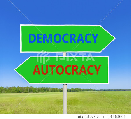 Democracy or autocracy words symbol. Concept words Democracy Autocracy on beautiful green road sign. Beautiful blue sky background. Business democracy autocracy concept. Copy space Democracy or autocracy words symbol. Concept words Democracy Autocracy on beautiful green road sign. Beautiful blue sky background. Business democracy autocracy concept. Copy space 141636061