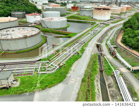 Aerial view of crude oil storage tank and pipeline system in a modern petrochemical plant. Efficient storage and transportation infrastructure in the oil and gas industry for safe fuel handling. Aerial view of crude oil storage tank and pipeline system in a modern petrochemical plant. Efficient storage and transportation infrastructure in the oil and gas industry for safe fuel handling. 141636421