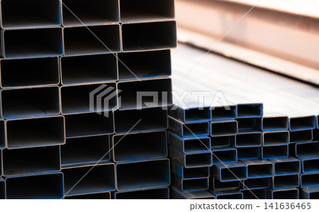 Industrial warehouse stock of rectangular metal pipes for building and construction supplies. Stack of steel pipes. Iron materials for construction and infrastructure projects. Steel tubing storage. Industrial warehouse stock of rectangular metal pipes for building and construction supplies. Stack of steel pipes. Iron materials for construction and infrastructure projects. Steel tubing storage. 141636465