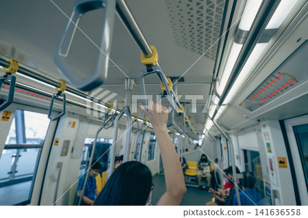 Woman hand firm grip safety handrail in elevated monorail train. Mass transit system in modern city. Inside of electric train. Tourist travel by city sky train. Public transportation. Urban transport. Woman hand firm grip safety handrail in elevated monorail train. Mass transit system in modern city. Inside of electric train. Tourist travel by city sky train. Public transportation. Urban transport. 141636558