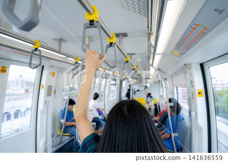 Woman hand firm grip safety handrail in elevated monorail train. Mass transit system in modern city. Inside of electric train. Tourist travel by city sky train. Public transportation. Urban transport. Woman hand firm grip safety handrail in elevated monorail train. Mass transit system in modern city. Inside of electric train. Tourist travel by city sky train. Public transportation. Urban transport. 141636559