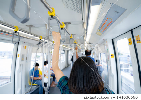 Woman hand firm grip safety handrail in elevated monorail train. Mass transit system in modern city. Inside of electric train. Tourist travel by city sky train. Public transportation. Urban transport. Woman hand firm grip safety handrail in elevated monorail train. Mass transit system in modern city. Inside of electric train. Tourist travel by city sky train. Public transportation. Urban transport. 141636560