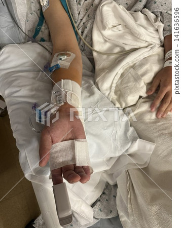 The hand of a patient resting in a hospital bed after catheter treatment. The hand of a patient resting in a hospital bed after catheter treatment. 141636596