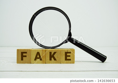 FAKE alphabet letters with magnifying glass on wooden background FAKE alphabet letters with magnifying glass on wooden background 141636653