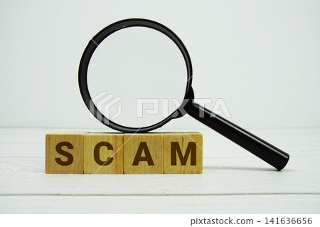 SCAM alphabet letters with magnifying glass on wooden background SCAM alphabet letters with magnifying glass on wooden background 141636656