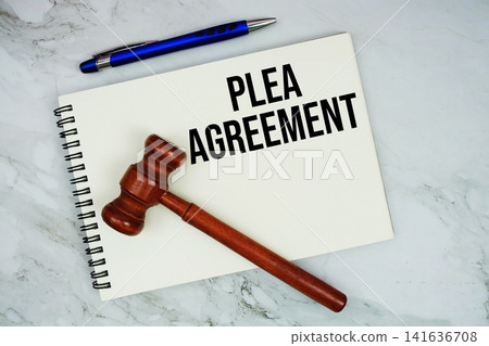 PLEA Agreement text written on notepad with pen and judge gavel on marble background PLEA Agreement text written on notepad with pen and judge gavel on marble background 141636708