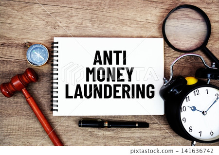 Anti Money Laundering message written on notepad with alarm clock, wood gavel and magnifying glass flat lay on wooden background Anti Money Laundering message written on notepad with alarm clock, wood gavel and magnifying glass flat lay on wooden background 141636742
