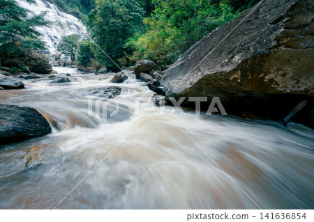 Beautiful waterfall in lush tropical green forest. Nature landscape. Mae Ya Waterfall is situated in Doi Inthanon National Park, Chiang Mai, Thailand. Waterfall flows through jungle on mountainside. Beautiful waterfall in lush tropical green forest. Nature landscape. Mae Ya Waterfall is situated in Doi Inthanon National Park, Chiang Mai, Thailand. Waterfall flows through jungle on mountainside. 141636854